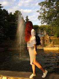 Side view of woman standing against fountain