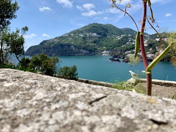 Scenic view of sea by mountains against sky