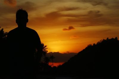 Silhouette man against orange sky