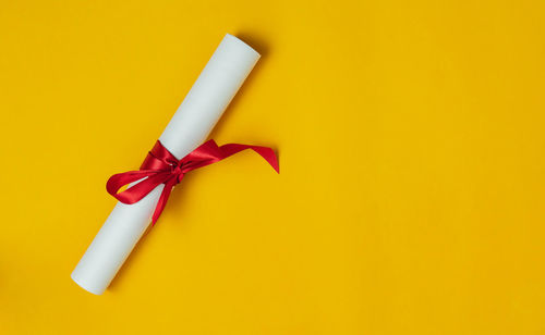Close-up of paper tied up on yellow background