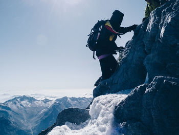 Side view of person rock climbing against clear sky during winter