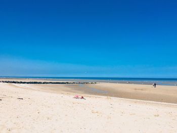 Scenic view of beach against blue sky