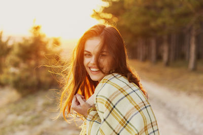 Portrait of smiling young woman standing against sky