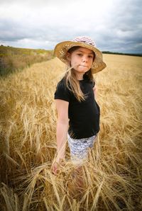Portrait of woman wearing hat standing on hay