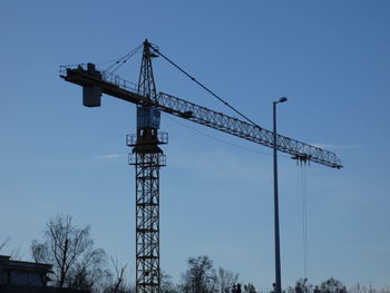 Low angle view of crane against clear blue sky