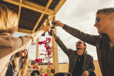 Cheerful friends toasting drinks at balcony