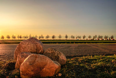 Hay bales on field against sky during sunset