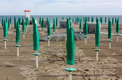 Chairs on wooden post at beach against sky