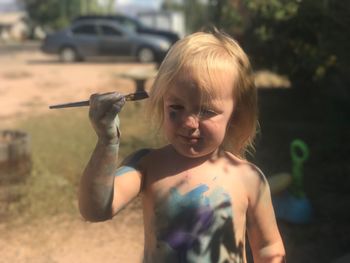 Close-up of shirtless girl with paintbrush