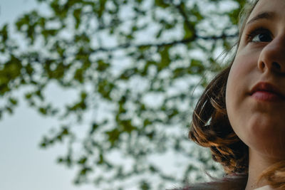 Low angle portrait of woman against tree