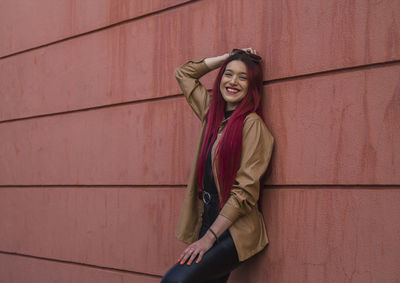 Happy young woman with long red hair on the wall