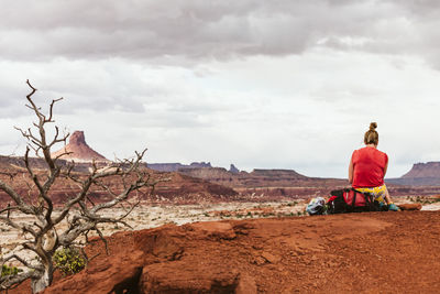 Female backpacker sits on her pack while taking a break in utah desert
