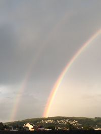 Rainbow over city against sky