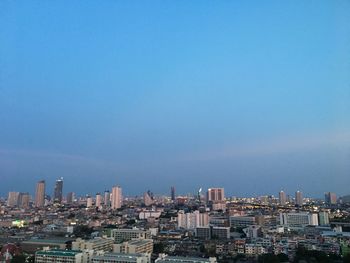 Buildings in city against clear blue sky