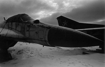 Abandoned airplane on sand at beach against sky