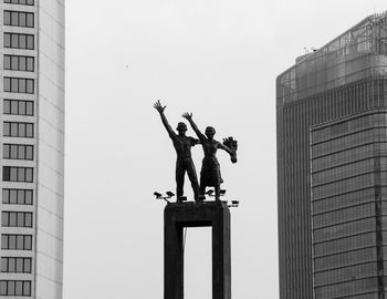 Low angle view of men on building against sky