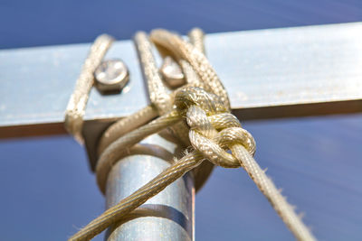 Close-up of rope tied on metal against sky