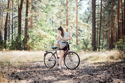 How to pack for bike ride, bicycle touring checklist. young woman with backpack riding bike in pine