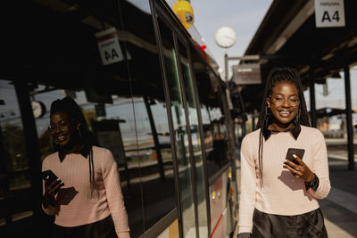 Young woman using cell phone at bus station