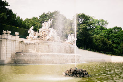 View of fountain by lake against sky