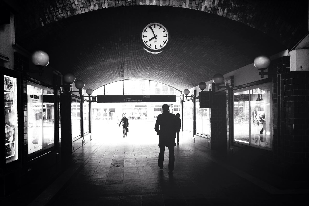 architecture, indoors, built structure, men, walking, lifestyles, full length, arch, illuminated, leisure activity, person, rear view, ceiling, building, building exterior, corridor, city life, tunnel