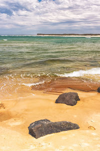 Scenic view of beach against cloudy sky