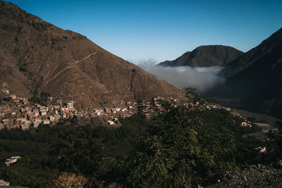 Scenic view of town by mountains against sky