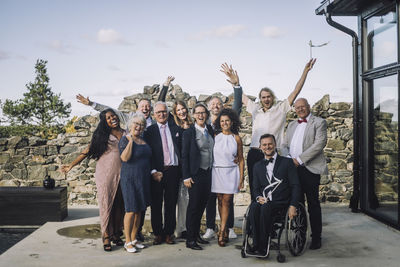 Portrait of cheerful family enjoying wedding ceremony on deck against sky