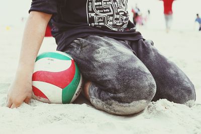 Low section of man sitting on beach