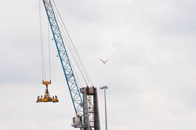 Low angle view of cranes against sky