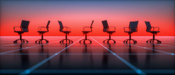 Empty chairs and table against sky during sunset