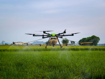 Drone used to fertilize  on field against sky