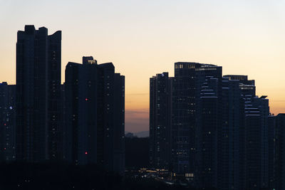 Buildings in city against clear sky during sunset