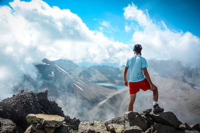 Rear view of man standing on rock against sky