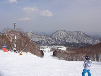 Rear view of person on snowcapped mountains against sky