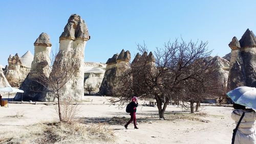 Rear view of woman walking against trees