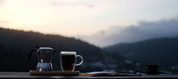 Coffee on table against mountains during sunset