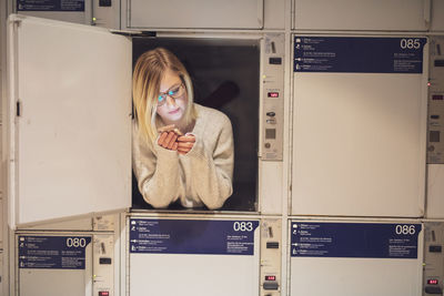 Young woman using phone in locker