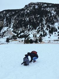 People on snow covered field against sky