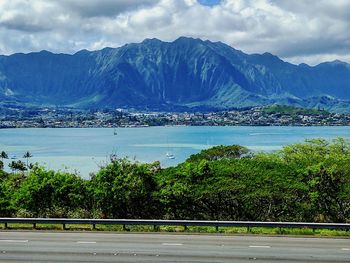 Scenic view of sea by mountains against sky