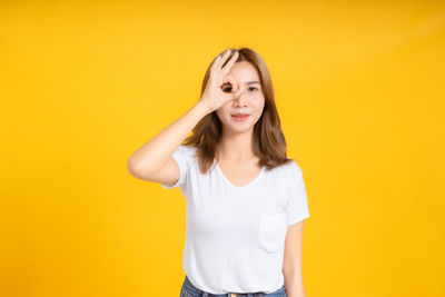 Portrait of smiling young woman against yellow background