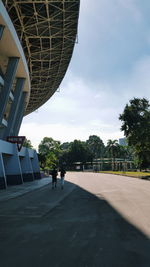 People walking in city against cloudy sky