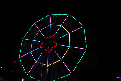 Illuminated ferris wheel against black background