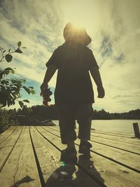Rear view of silhouette boy standing against sky