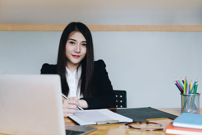 Portrait of smiling businesswoman working at desk in office