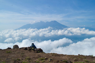 Rear view of hiker on mountain peak against sky