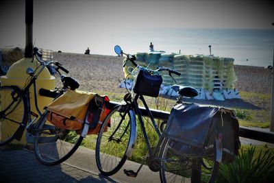 Bicycles parked on land by sea against sky