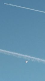 Low angle view of vapor trails in blue sky