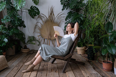 Stress relief after work. relaxed young girl spend time in cozy indoor garden with monstera plant