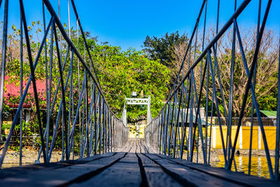 Footbridge amidst trees in city against sky
